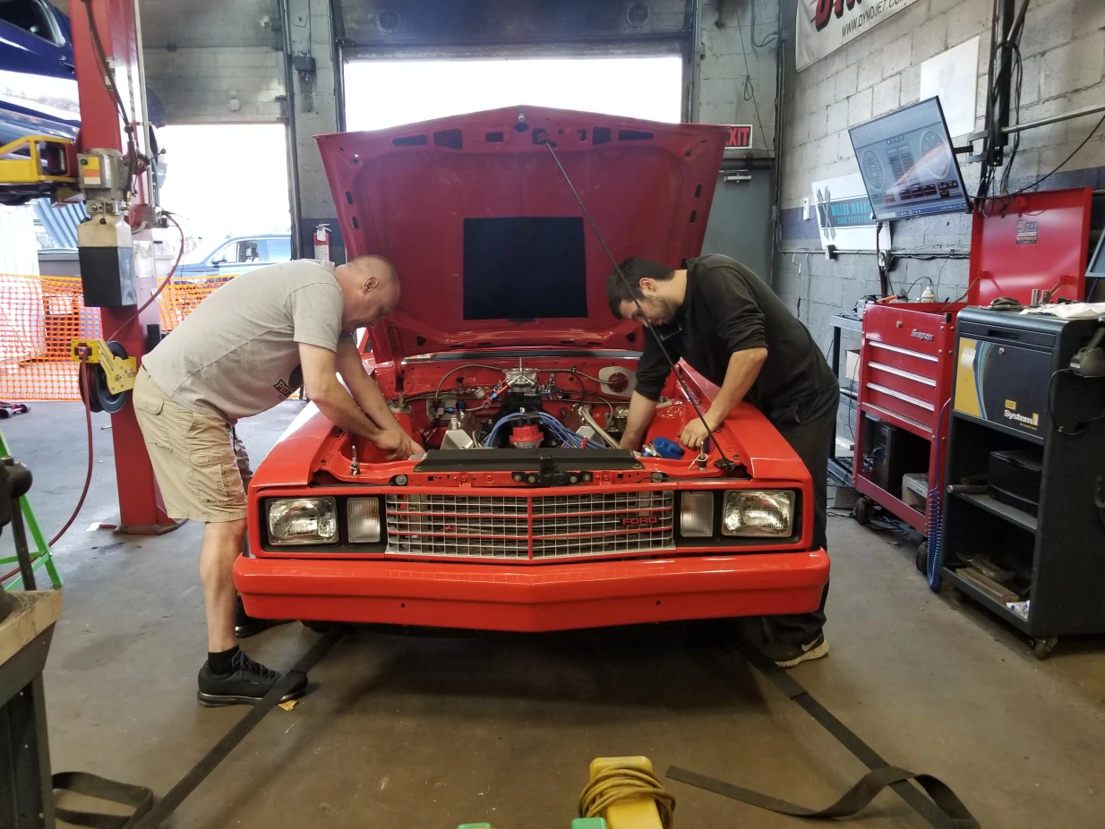 Team working under the hood of Orange Ford Fairmont 1 Team working under the hood of Orange Ford Fairmont